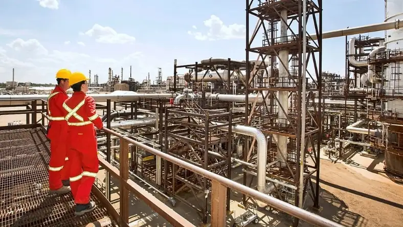Engineers in safety gear overlooking industrial carbon capture facility